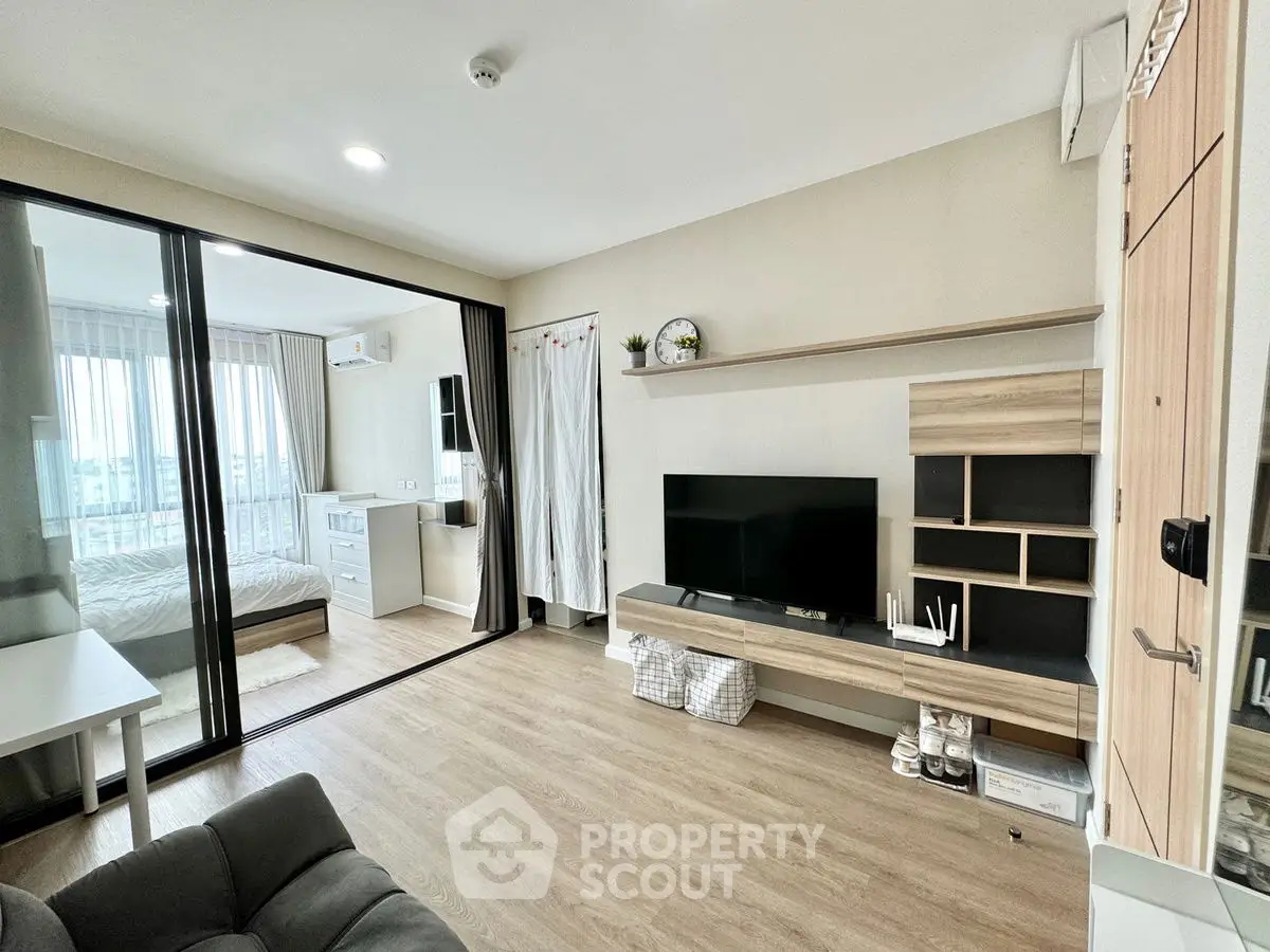 Modern living room with sleek design and sliding glass doors leading to a cozy bedroom.