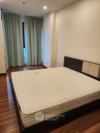 Spacious bedroom with wooden flooring and large windows for natural light