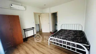 Spacious bedroom with wooden flooring and modern furnishings in a well-lit apartment.