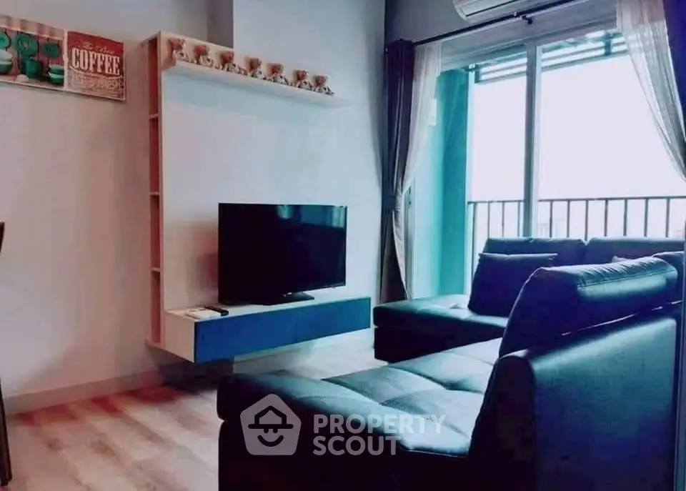 Modern living room with sleek furniture and large window offering natural light.