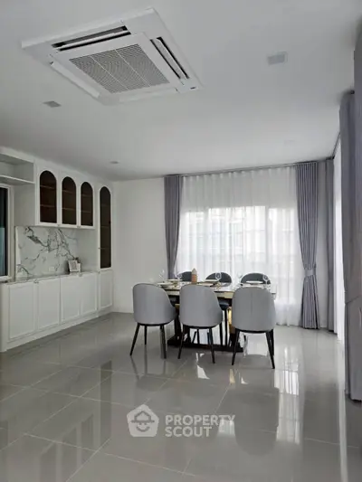 Elegant dining area with modern furniture and large windows in a spacious home.