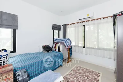 Cozy bedroom with natural light and air conditioning, featuring a single bed and wardrobe.