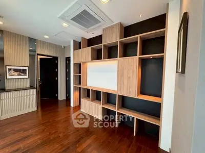 Modern living room with stylish wooden shelving and elegant hardwood flooring.
