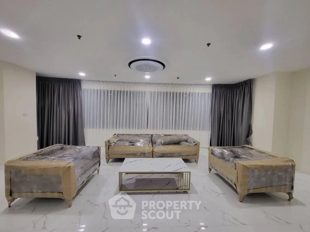 Spacious modern living room with elegant marble flooring and stylish furniture.