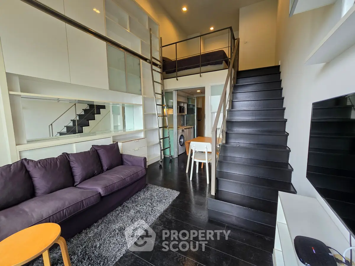 Modern loft apartment with mezzanine, sleek black staircase, and cozy living area.