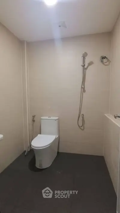 Modern bathroom with sleek toilet and shower fixtures in minimalist design.