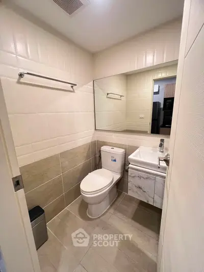 Modern bathroom with sleek fixtures and large mirror in a contemporary apartment.