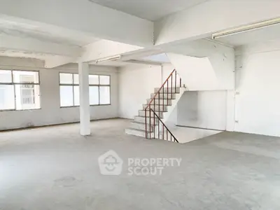 Expansive open-plan loft space with abundant natural light, high ceilings, and a modern staircase, perfect for a bespoke interior design.