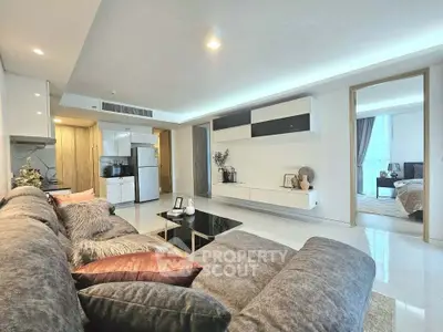 Spacious modern living room with plush sofa and open view to bedroom, ideal for luxury urban living.