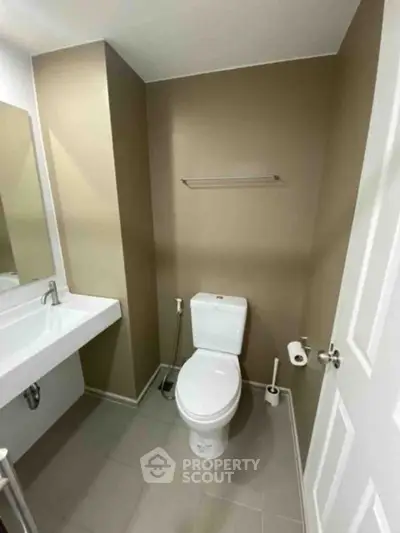 Modern bathroom with sleek fixtures and neutral tones, featuring a toilet and sink.
