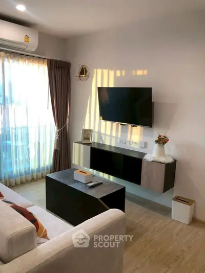 Modern living room with wall-mounted TV and stylish decor, featuring natural light and cozy ambiance.