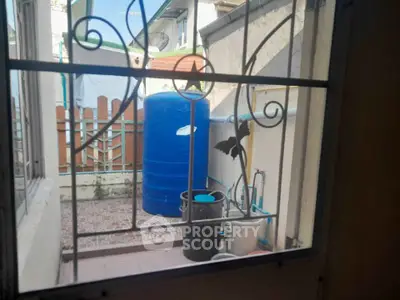 Charming outdoor utility area with water tank and decorative window grill