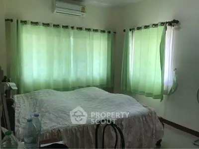 Cozy bedroom with green curtains and air conditioning, perfect for relaxation.