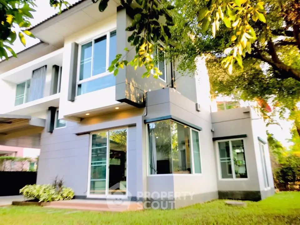 Modern two-story house with large windows and lush greenery