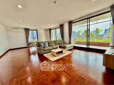 Spacious living room with large windows and city view, featuring elegant wooden flooring and modern furniture.