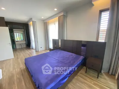 Spacious modern bedroom with elegant wooden flooring and large windows for natural light.