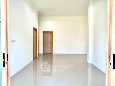 Spacious empty room with high ceiling and tiled floor, perfect for customization.