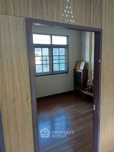 Cozy room with wooden flooring and large window offering natural light.