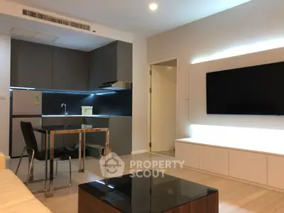 Modern open-layout living room with sleek kitchen and large TV setup.