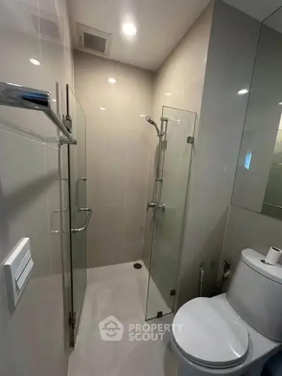 Modern bathroom with glass shower and sleek fixtures in a contemporary apartment.
