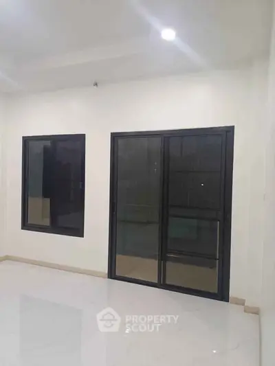 Spacious room with large windows and sliding glass doors, perfect for natural light.
