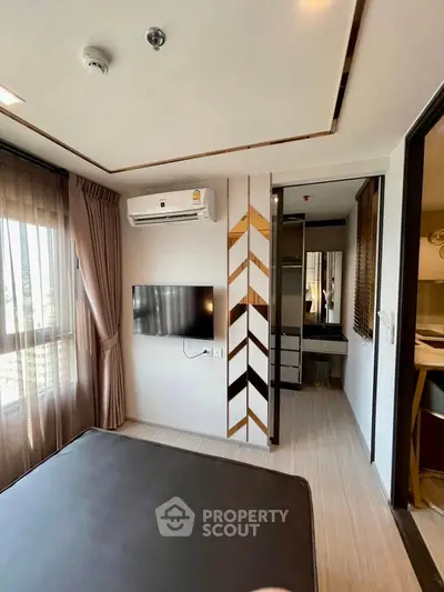 Modern bedroom with wall-mounted TV and air conditioning, featuring stylish decor and ample natural light.
