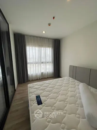 Modern bedroom with large window and elegant curtains, featuring a comfortable bed and minimalist design.