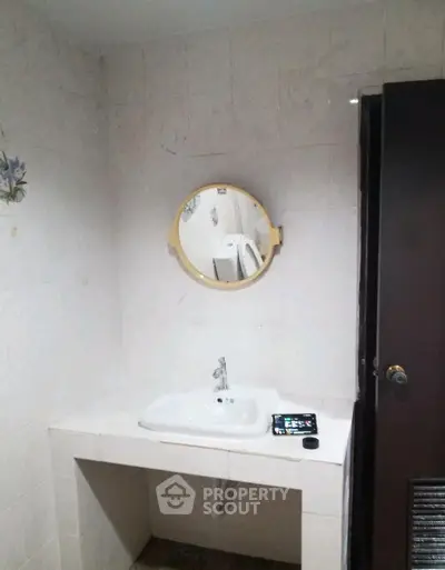 Cozy bathroom with round mirror and modern sink in a stylish real estate property.