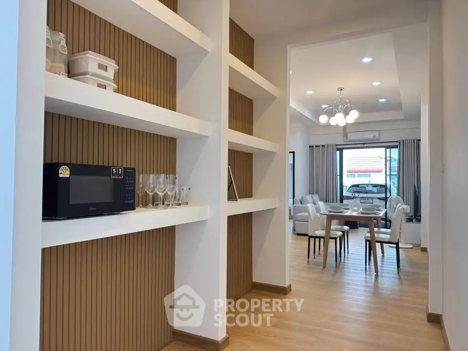 Modern open-plan living and dining area with stylish shelving and natural light.