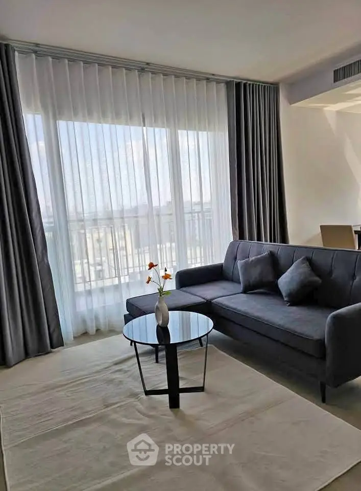 Modern living room with elegant sofa and floor-to-ceiling windows offering natural light and a stylish ambiance.
