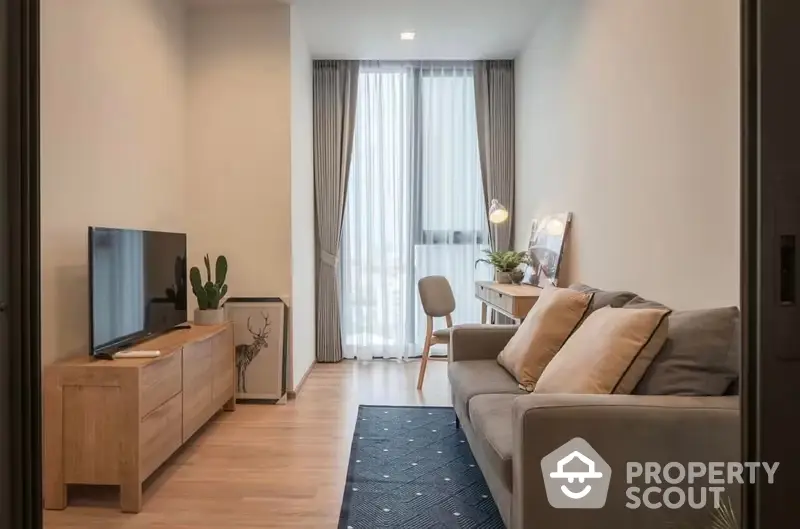 Cozy and modern living room with natural light, comfortable sofa, and wooden furniture, leading to a bright balcony area.