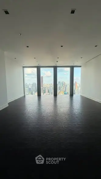 Spacious empty room with floor-to-ceiling windows offering stunning city skyline views.