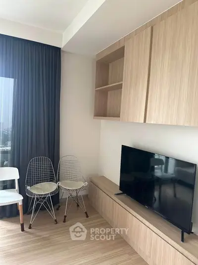 Modern living room with sleek wooden cabinetry and flat-screen TV, featuring stylish wire chairs and floor-to-ceiling curtains.
