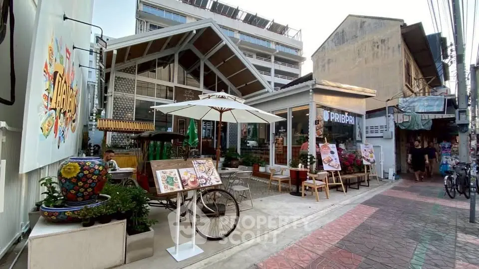 Charming street view of a modern cafe with outdoor seating and vibrant decor in an urban setting.