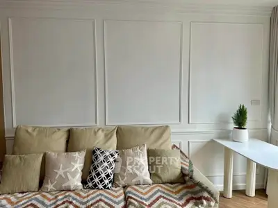 Elegant living room with stylish sofa and decorative pillows, featuring a chic side table and minimalist decor.