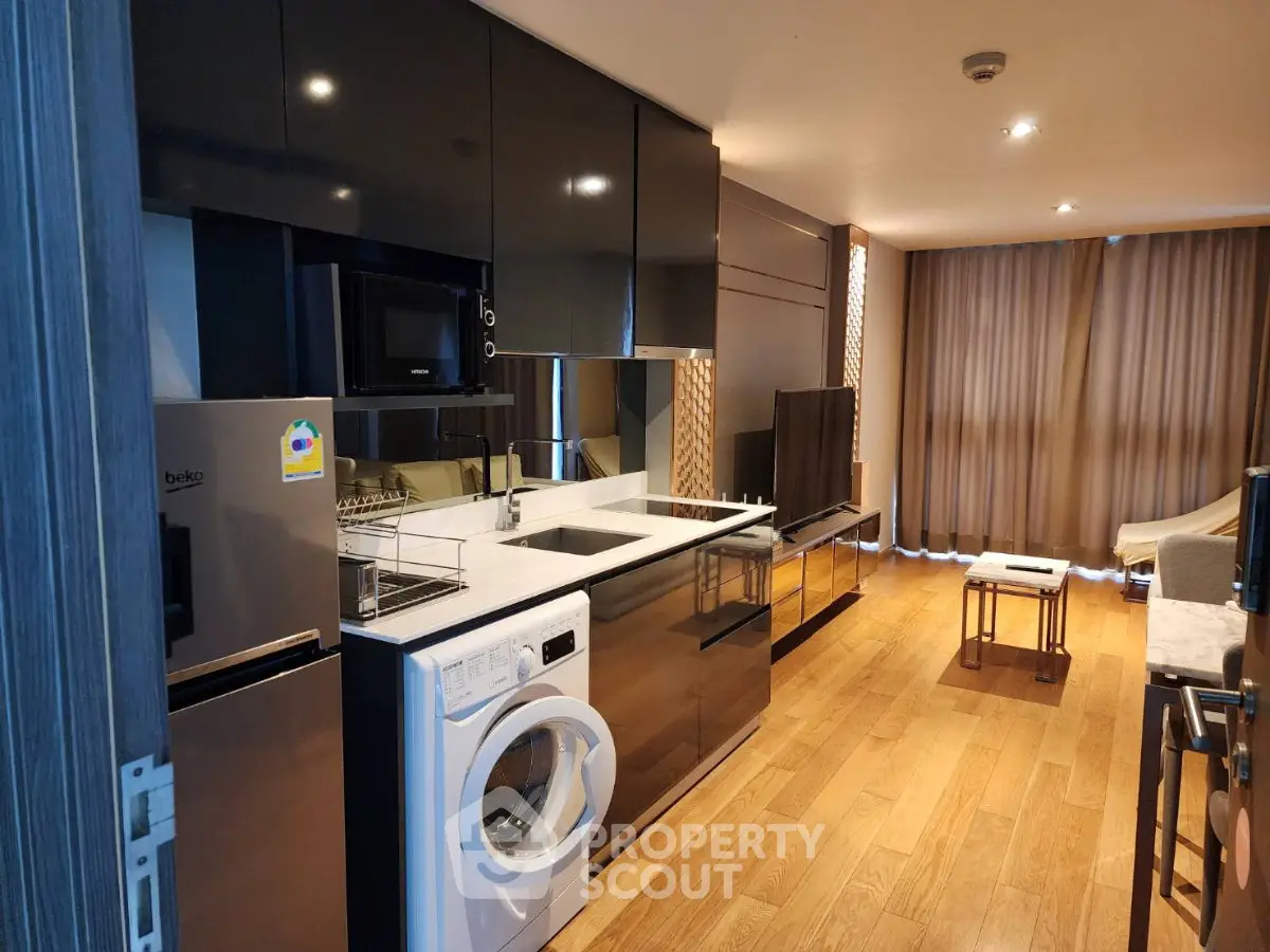 Modern kitchen with sleek black cabinets and integrated appliances in a stylish apartment.