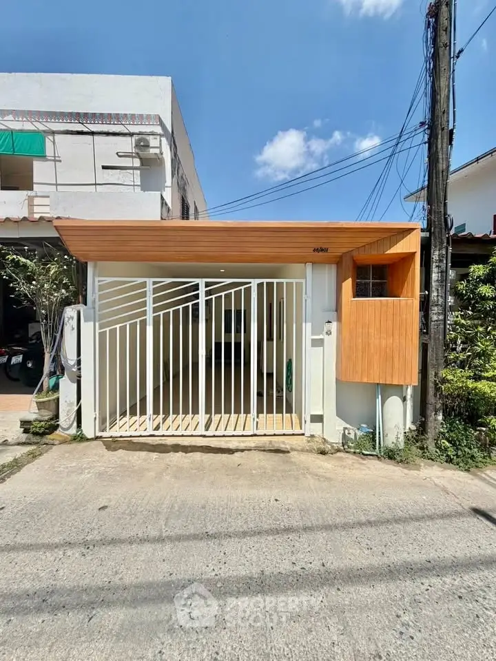 Modern minimalist house exterior with wooden accents and white gate, perfect for urban living.