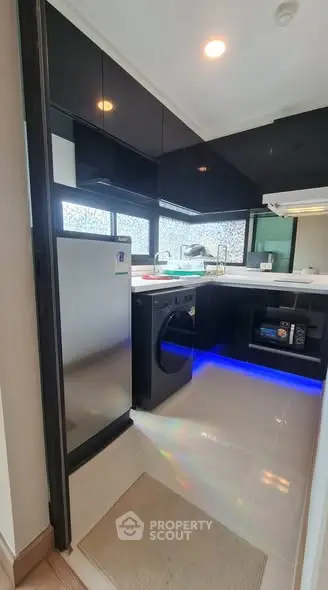 Modern kitchen with sleek black cabinets, stainless steel fridge, and built-in appliances.