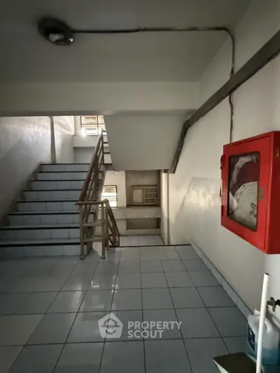 Stairwell in residential building with emergency equipment and tiled flooring
