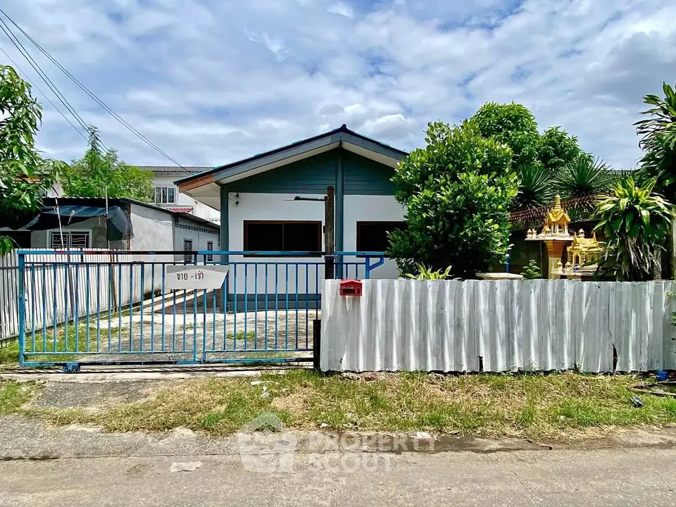 Charming single-story house with gated entrance and lush greenery, perfect for serene living.