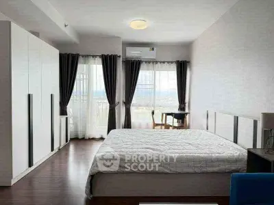 Spacious bedroom with large windows and modern furnishings, offering a serene view.