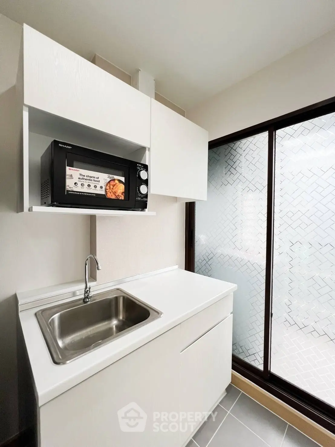 Modern kitchen with sleek cabinetry and built-in microwave in bright apartment