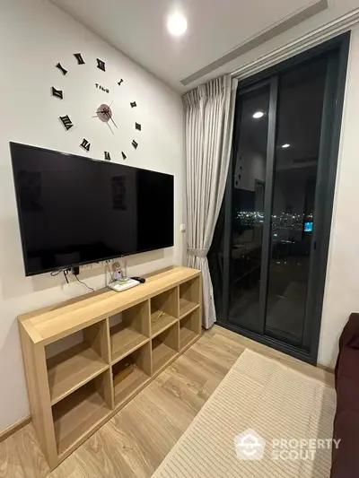 Modern living room with wall-mounted TV and large window offering city view