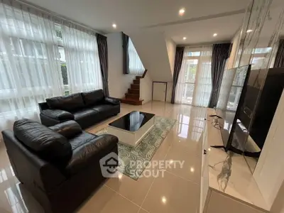 Spacious modern living room with sleek black leather sofas and large windows