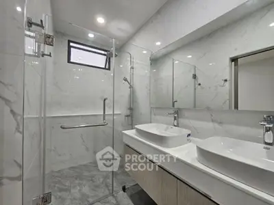 Modern bathroom with dual sinks and glass shower enclosure in sleek design.