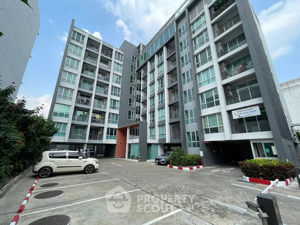 Modern apartment building with spacious parking area and contemporary design.