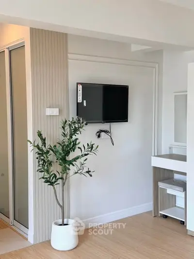 Modern interior with wall-mounted TV and potted plant, showcasing minimalist design and sleek finishes.
