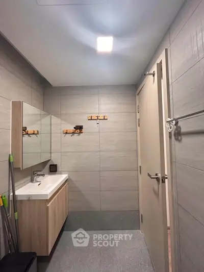 Modern bathroom with sleek vanity and wall-mounted mirror in contemporary apartment.