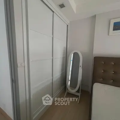 Modern bedroom with sleek sliding closet doors and stylish standing mirror.