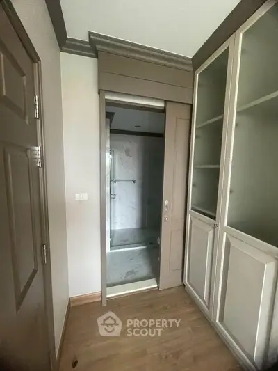 Modern interior with sliding door leading to a sleek bathroom, featuring elegant cabinetry and wood flooring.